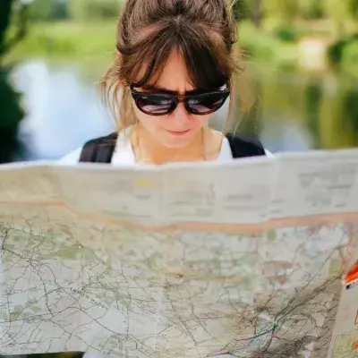 Eine Frau mit Sonnenbrille schaut in eine Landkarte