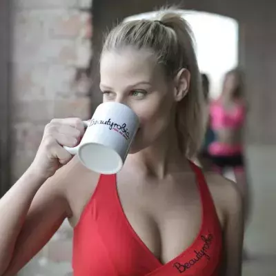 Frau in rotem Sportoberteil trinkt einen Kaffee