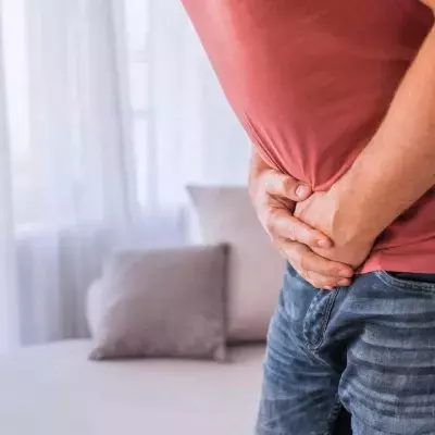 Mann krümmt sich und presst Hände an den Bauch