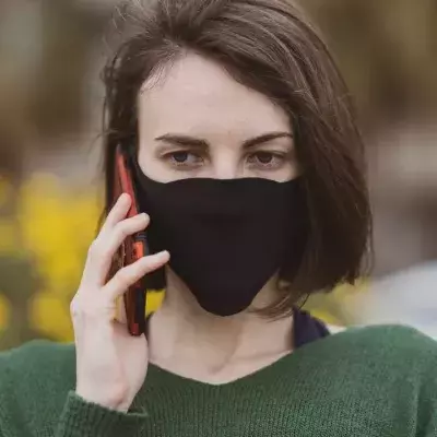 A woman talking on the phone with coronavirus mask