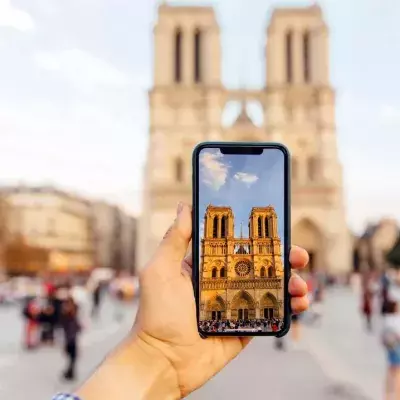 Tourist taking picture of Notre Dame cathedral with smart phone, personal perspective view