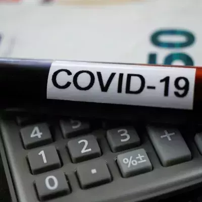 Berechnung des wirtschaftlichen Schadenskonzepts: covid-19 Blutprobenröhre auf Rechner, verschwommener 50-Euro-Scheinhintergrund