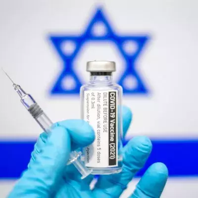 Eine Hand mit Impfstoff vor israelischer Flagge