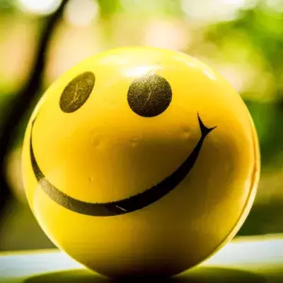 Ein gelber Ball mit Smiley-Gesicht vor grünem Hintergrund 
