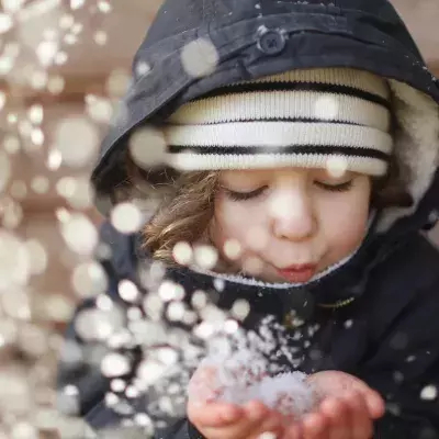 Kind pustet Schnee
