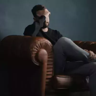 Mann hält Kopf auf Couch