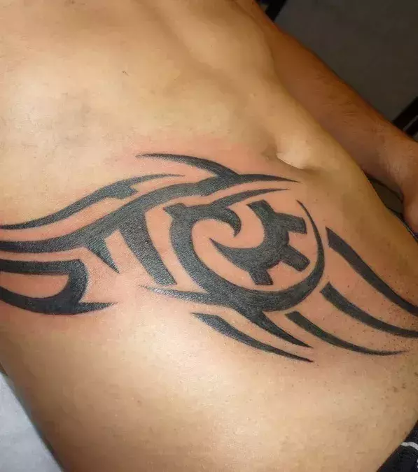 Auf dem Bauch von einem Mann: ein Tribal Tattoo