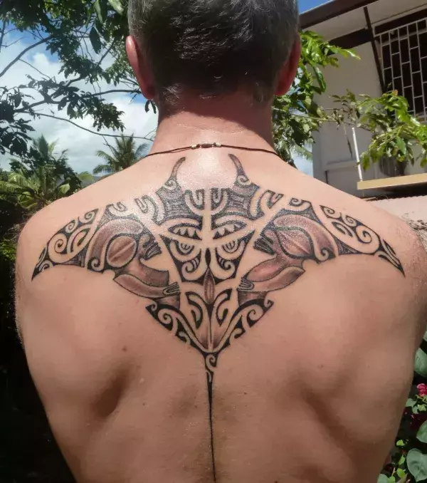 Auf dem Rücken eines Mannes: ein Rochen Tribal Tattoo