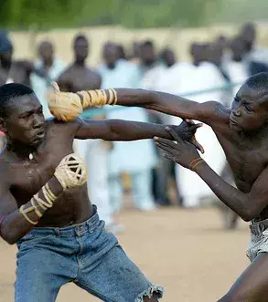 Dambe ist das traditionelle Boxen aus Nigeria mit spektakulärer Brutalität und wird auf Sand praktiziert. Die Kämpfer benutzen ihren schwachen Arm, um eine Verbindung mit dem Gegner herzustellen und den anderen, um egal welchen Körperteil zu treffen