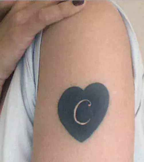 Der Buchstabe C in einem Herz als Tattoo auf dem Arm