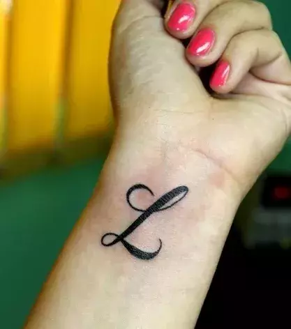 Der Buchstabe L in femininer Schrift als Tattoo auf dem Handgelenk