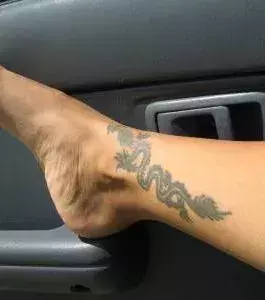 Drachen Tattoo auf dem Fußknöchel eines Mannes
