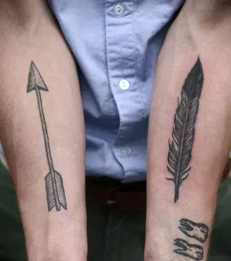Ein von Indianern inspiriertes Tattoo: Pfeil und Feder Tattoo auf den Unterarmen