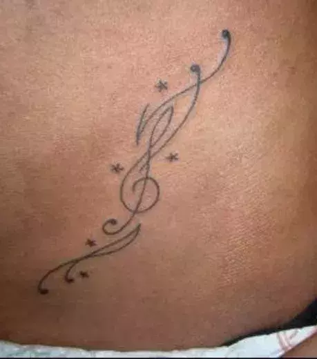 Notenschlüssel Tattoo auf der Leiste eines Mannes