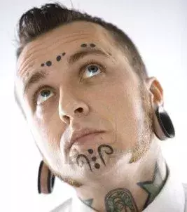 Punkte Tattoo im Gesicht eines Mannes