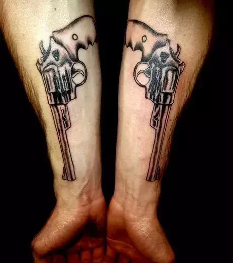Revolver Tattoo auf den Unterarmen eines Mannes