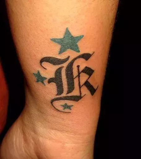 Tattoo des Buchstaben K mit Sternen auf dem Arm