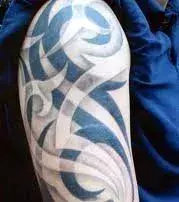 Tattoo einer Frau: Tribal Symbole auf dem Oberarm