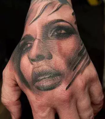 Tattoo mit dem Gesicht einer Frau auf der Hand eines Mannes