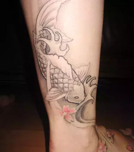 Tattoo mit einem chinesischen Fisch auf der Wade von einem Mann