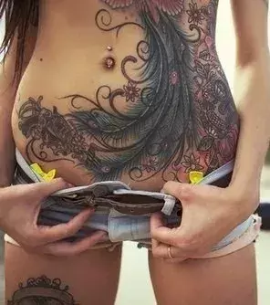Tattoos für Frauen: Auf dem Bauch dieser Frau befindet sich ein tolles Pfauen Tattoo