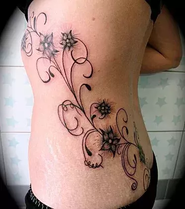 Tattoos für Frauen: Blumen Tattoo auf den Rippen und dem Steißbein einer Frau