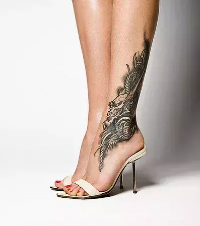 Tattoos für Frauen: Drachen Tattoo auf der Wade einer Frau