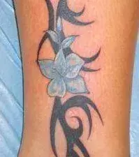 Tattoos für Frauen: Tribal Tattoo mit Blume auf der Wade einer Frau