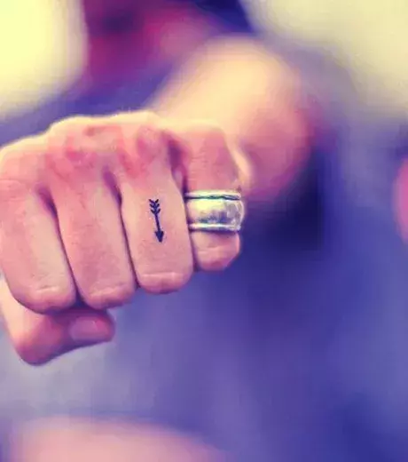 Winziges Tattoo mit Pfeil auf dem Finger von einem Mann