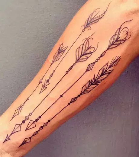 Zarte Pfeile mit Federn als Tattoo auf dem Arm eines Mannes